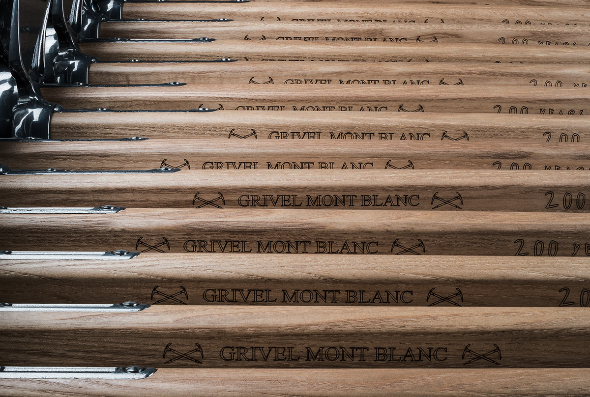 Rows of Grivel Monte Bianco wooden shaft ice axes showing engraved ash handles.